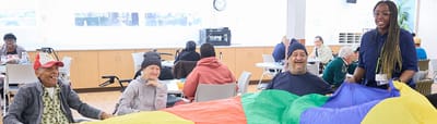 Residents participating in a group activity with colorful parachute.