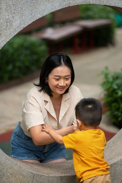 Woman engaging with a child in a garden area.