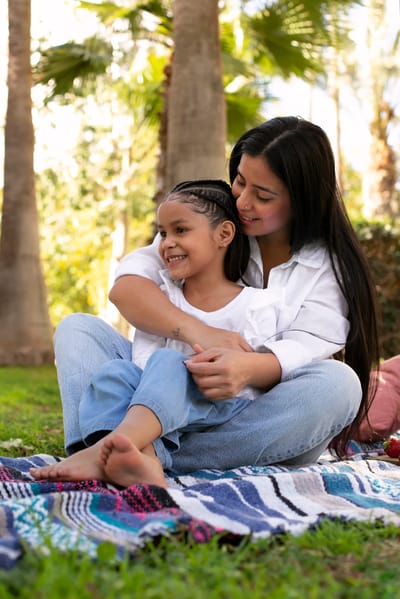 A woman hugging a girl in a garden.