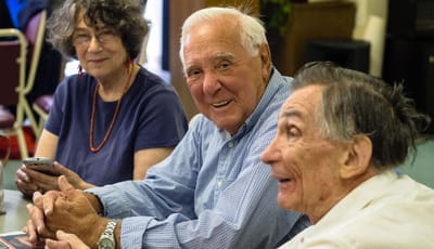 Three residents engaged in conversation indoors.