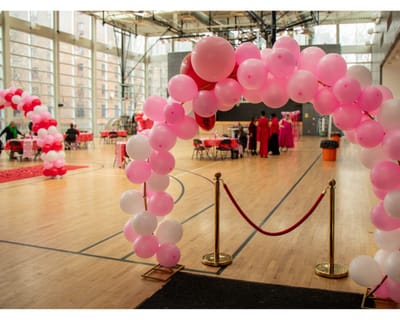 A festive interior with pink balloon arch and tables