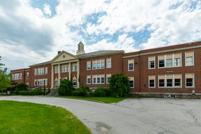 Exterior view of a large brick building with green grass.