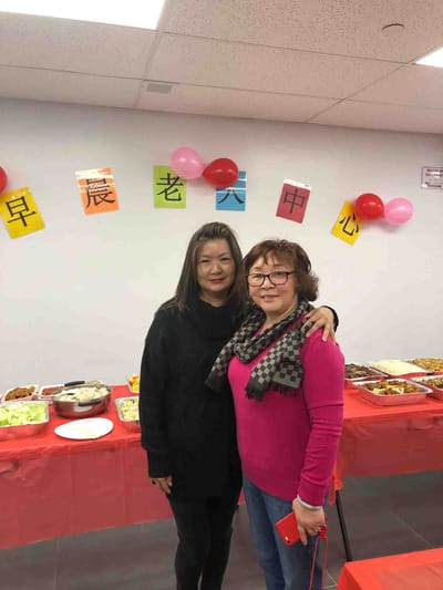 Two women celebrating with food in a decorated room.