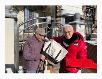 Two men smiling while holding bags outdoors.