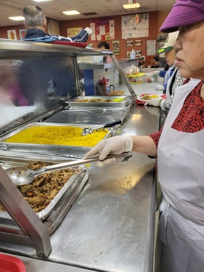 Resident serving food in a dining setting.