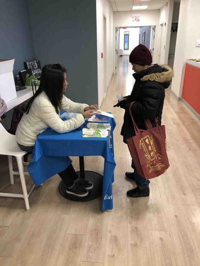 Staff assisting resident at a table in the hallway.