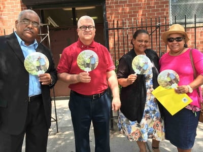 Four people holding fans outside a building