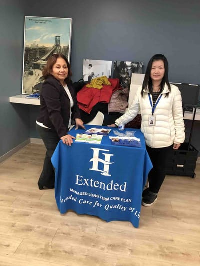 Two staff members at a table with informational materials.