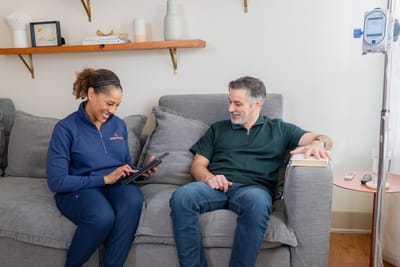 Staff member assisting a resident on the couch.