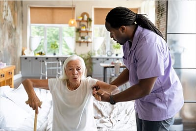 Caregiver assisting an elderly woman in a bedroom