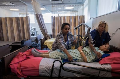 Two staff members assisting a resident in a care setting.