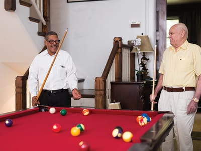 Two seniors playing billiards indoors