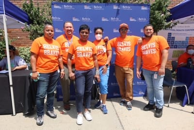 Group of staff members in orange shirts outdoors.