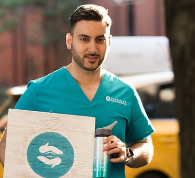 Staff member in scrubs standing outside