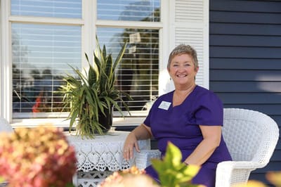 Staff member smiling in an outdoor seating area.