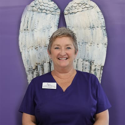 Staff member smiling in front of decorative wings