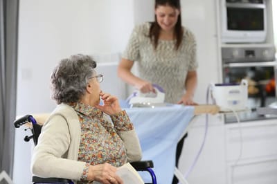 Elderly woman watching staff ironing clothes.