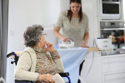 Resident being assisted with laundry by staff.