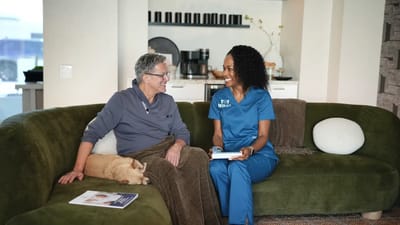 A staff member engaging with a resident in a cozy interior.
