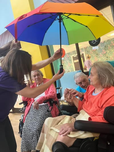 Residents enjoying indoor activities with colorful umbrella