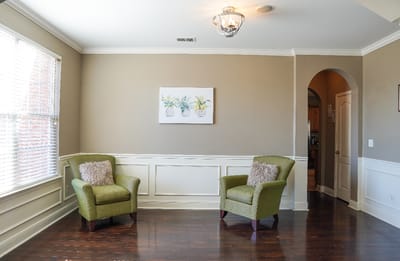 A bright, empty sitting area with green chairs