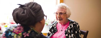 Smiling elderly woman interacting with caregiver.