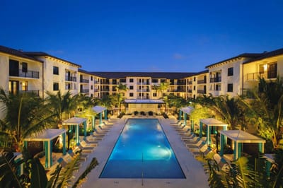 Overview of a pool area surrounded by buildings and palm trees.