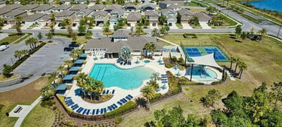 Aerial view of a pool area with cabanas and tennis courts.