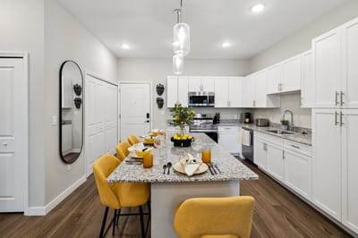 Modern kitchen with dining area and yellow chairs.