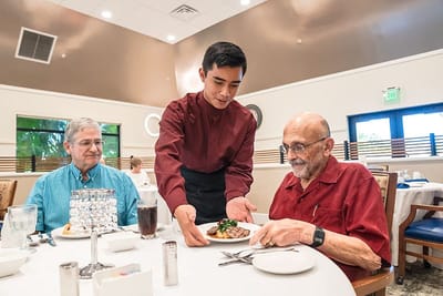 Residents enjoying a meal served by staff.