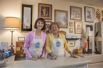 Two women smiling in an interior retail space.