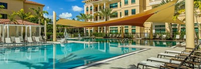 Outdoor pool area with lounge chairs and shade sails.
