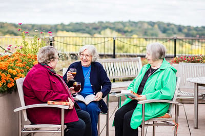 Three residents enjoying drinks on a patio