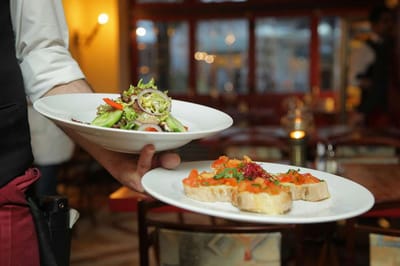 Waiter serving salad and bruschetta in restaurant