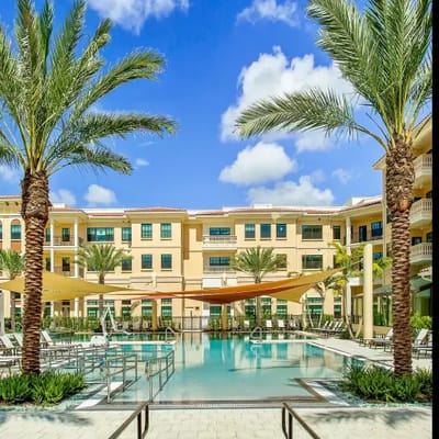 Outdoor pool area with palm trees and building in background