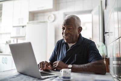 Senior man using a laptop in the kitchen