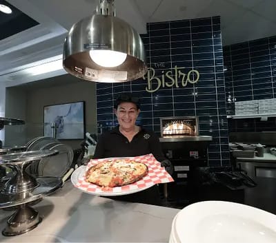 Staff member serving a pizza in the dining area