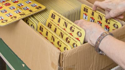 Hands organizing bingo cards in a box.