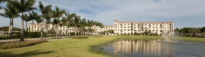 Exterior view of the facility with palm trees and pond.
