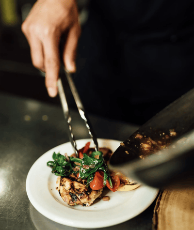 Chef plating grilled chicken with vegetables