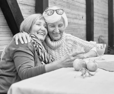 Two senior women enjoying a drink and laughing together.
