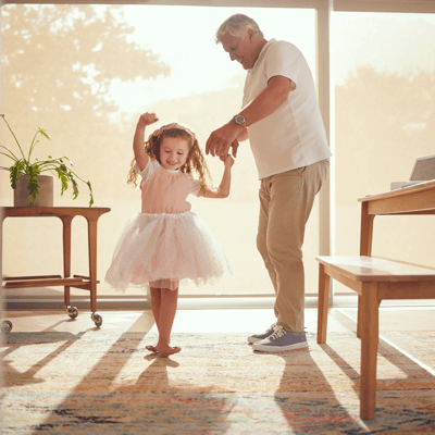 A child dancing with an elderly man indoors.