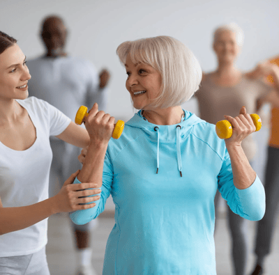 Senior participating in an exercise class with a staff member.