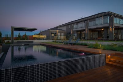 Outdoor pool area at sunset with a building in the background.