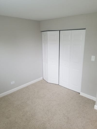 Empty resident room with beige carpet and closet