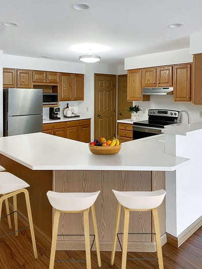 Modern kitchen with seating and fruits on the counter.