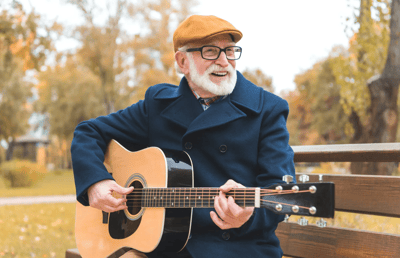 Elderly man playing guitar in a park