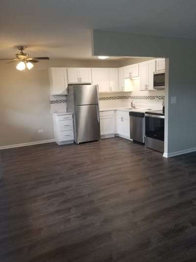 Modern kitchen area with appliances and wood flooring.