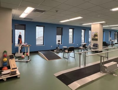 Rehabilitation space with exercise equipment and windows.