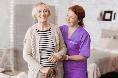 A caregiver assisting a senior resident in a cozy room